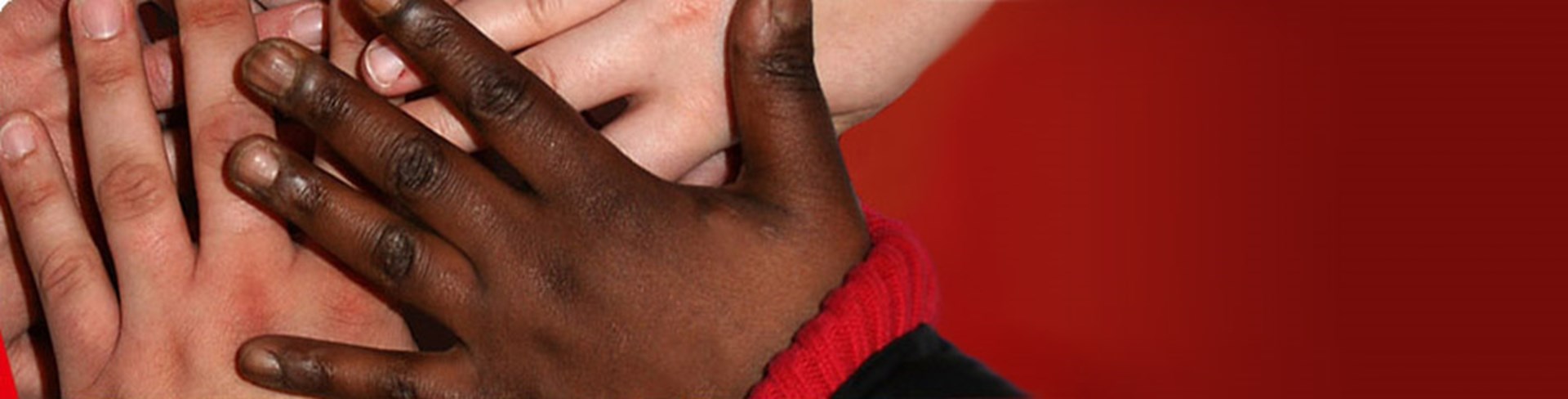 Hände mehrerer Kinder unterschiedlicher Hautfarbe übereinander 