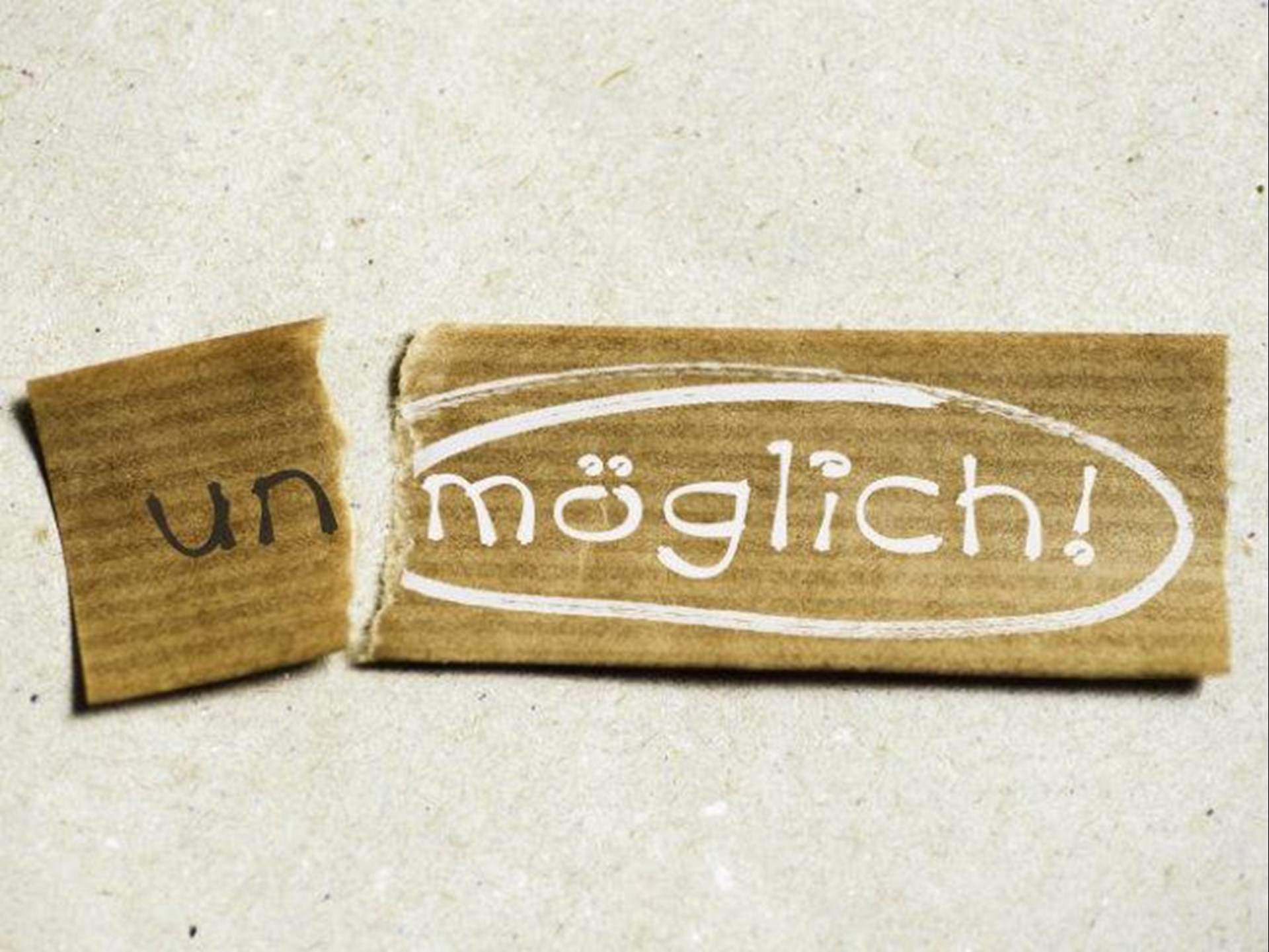 Das Wort "Unmöglich" auf einem Karton, das "un" ist abgerisssen