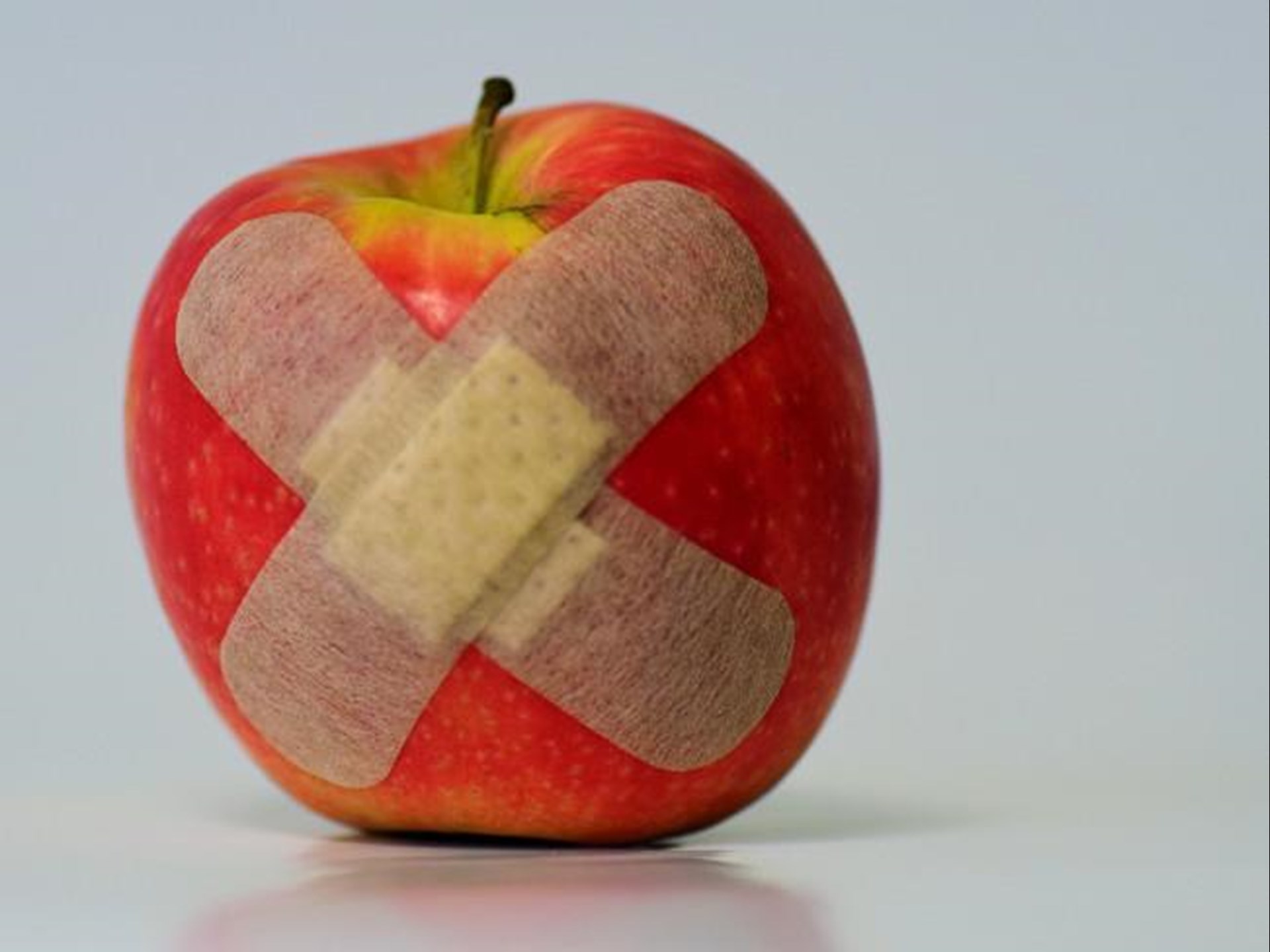 Zwei Pflaster kleben auf einem roten Apfel